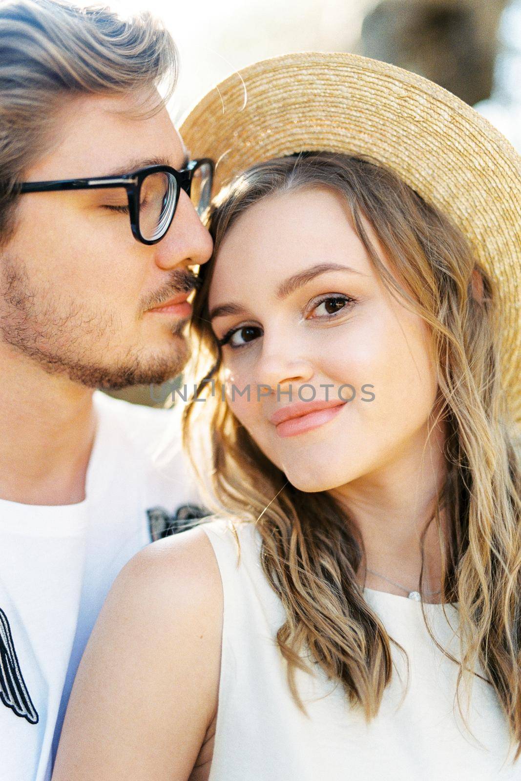 Man in glasses touches his lips the forehead of a smiling woman. Portrait. High quality photo