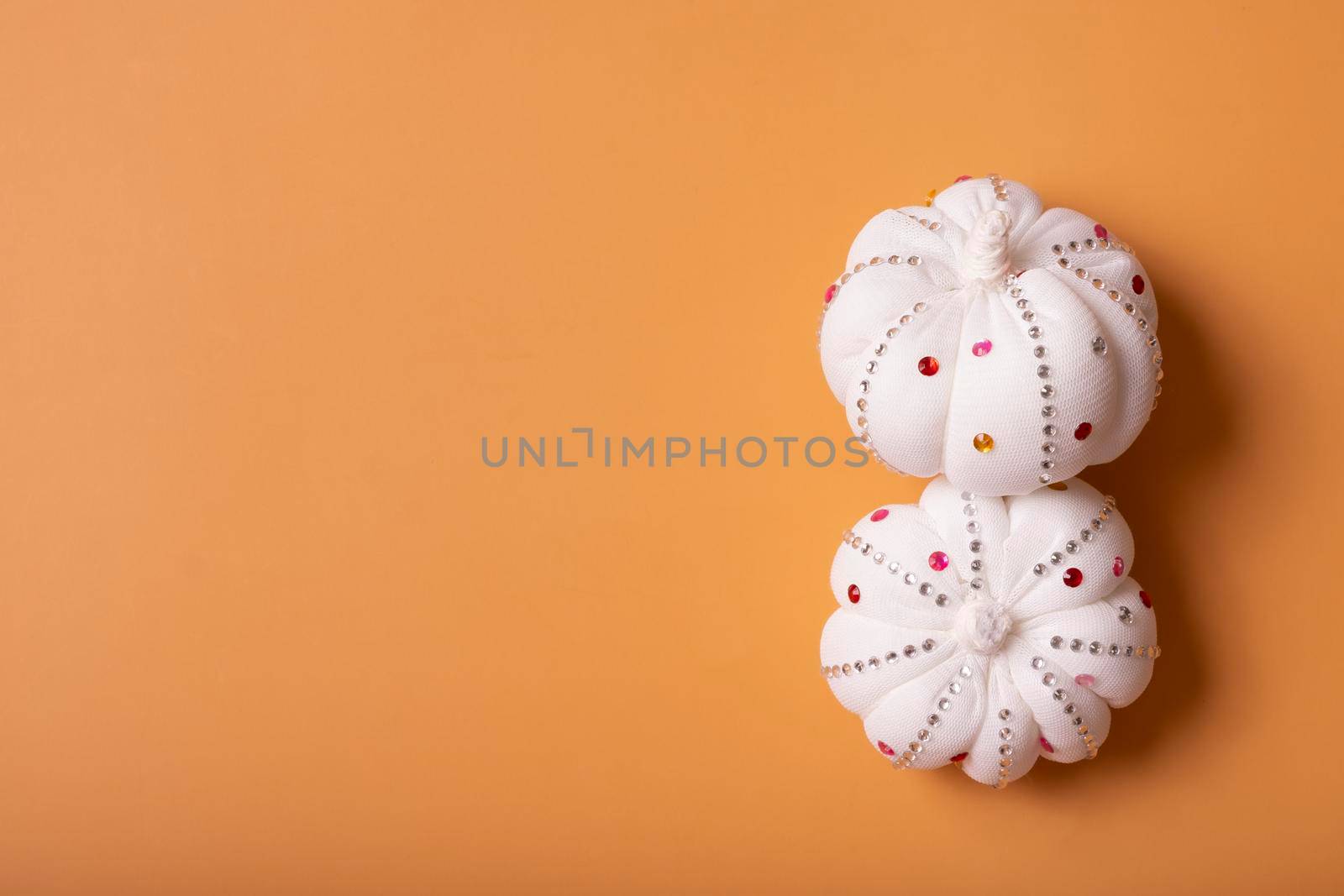 White decorative textile pumpkins with shiny stones with copy space. Autumn harvest concept.