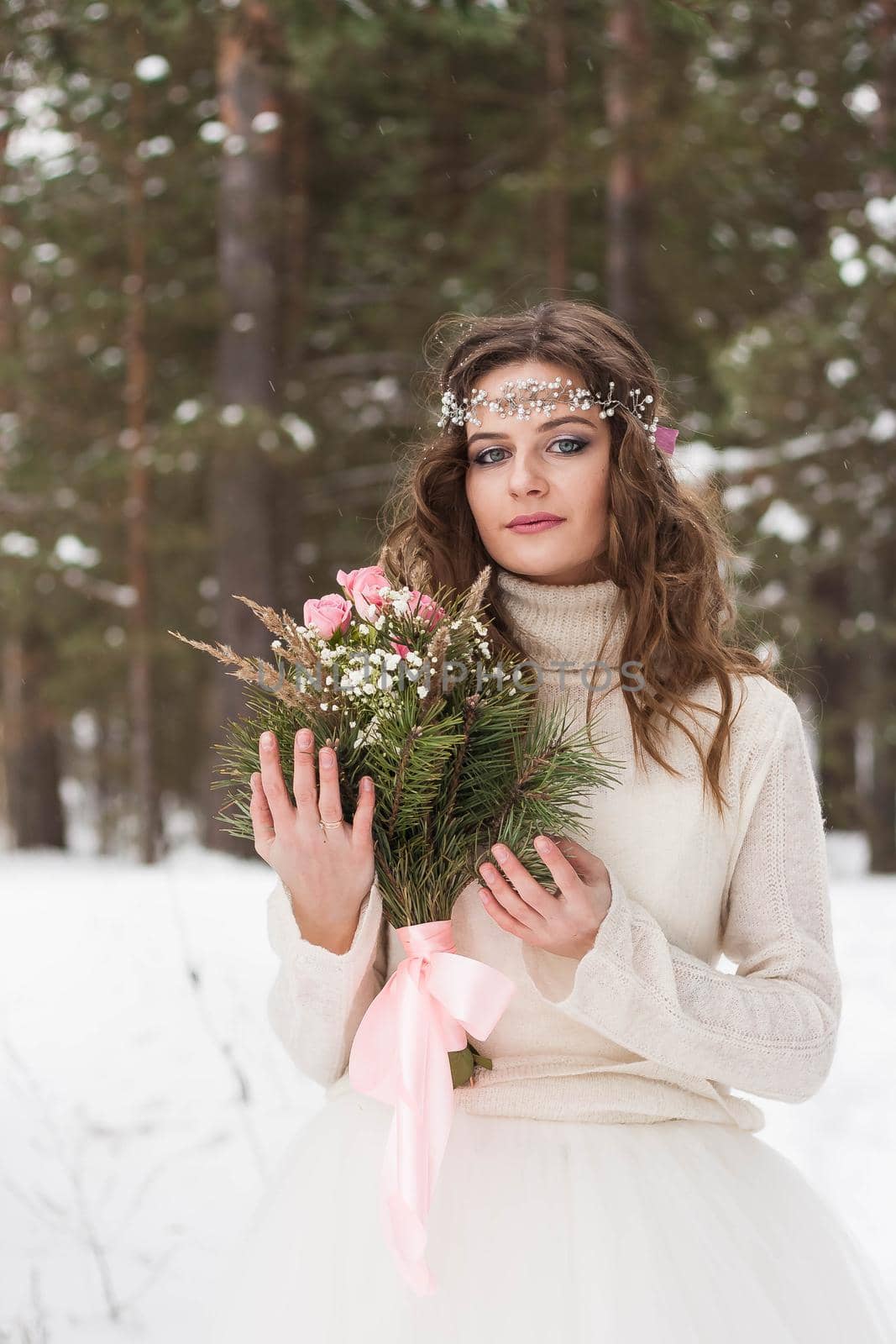 Beautiful bride in a white dress with a bouquet in a snow-covered winter forest. Portrait of the bride in nature.Beautiful bride in a white dress with a bouquet in a snow-covered winter forest. Portrait of the bride in nature.