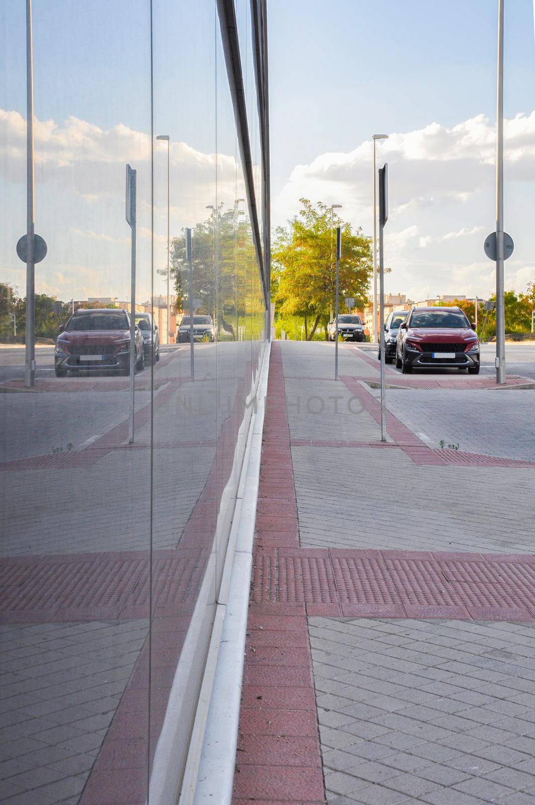 Street with cars reflected on a glass building in Madrid