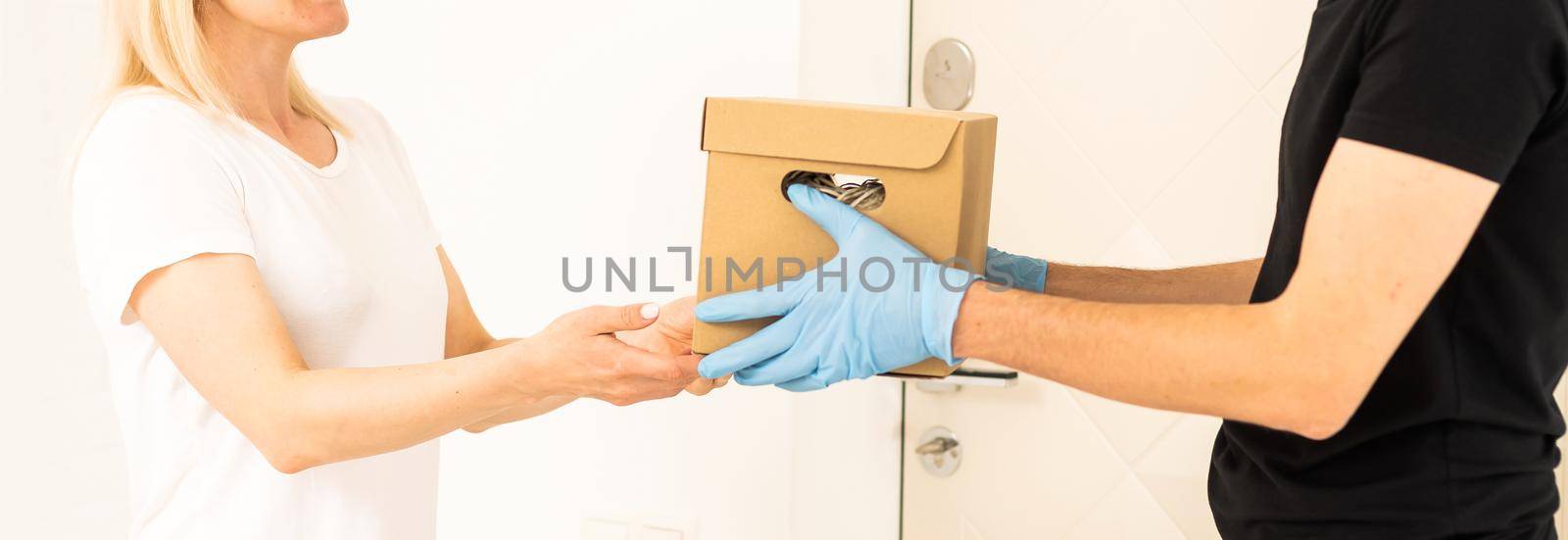 Courier in protective mask and medical gloves delivers takeaway food. Delivery service under quarantine, disease outbreak, coronavirus covid-19 pandemic conditions
