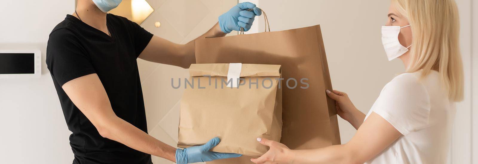 The shipper wears a mask and gloves, delivery food to the home of the online buyer. stay at home reduce the spread of the covid-19 virus. The sender has a service to deliver products or food quickly