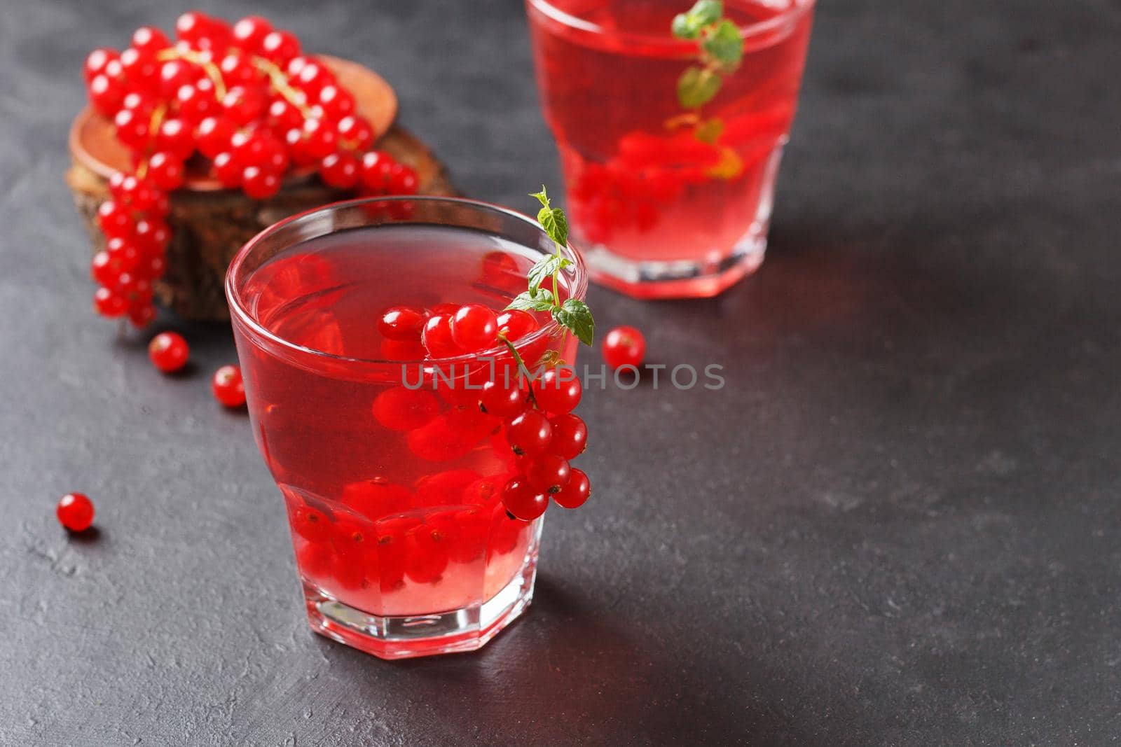 Redcurrant vitamin drink in a glass on a black background with currant berries. healthy eating. Copy space