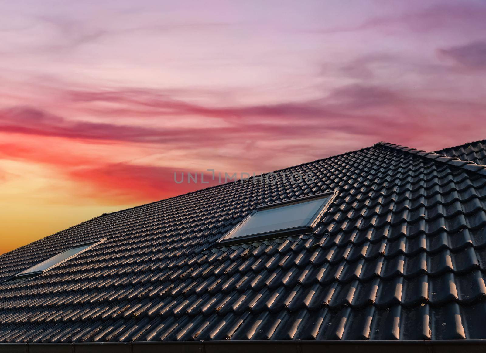 Open roof window in velux style with black roof tiles during sunset. by MP_foto71