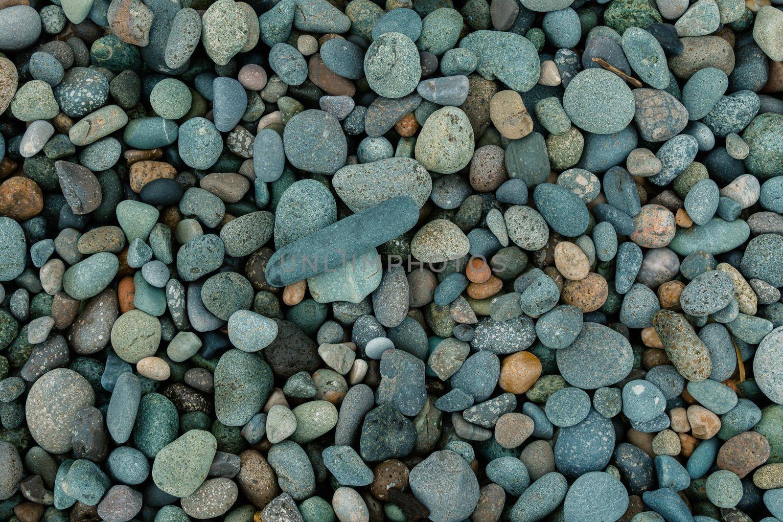 Natural rounded gravel on the seashore nature background texture pattern. Pebble beach stones background.