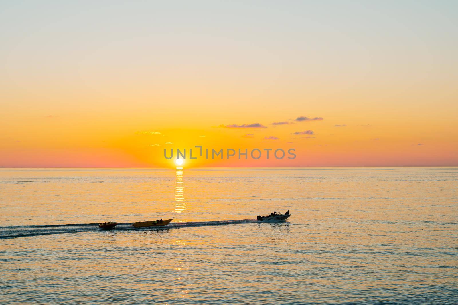Sunset over the sea with a sailing boat in the distance. Beautiful seascape from the shore.