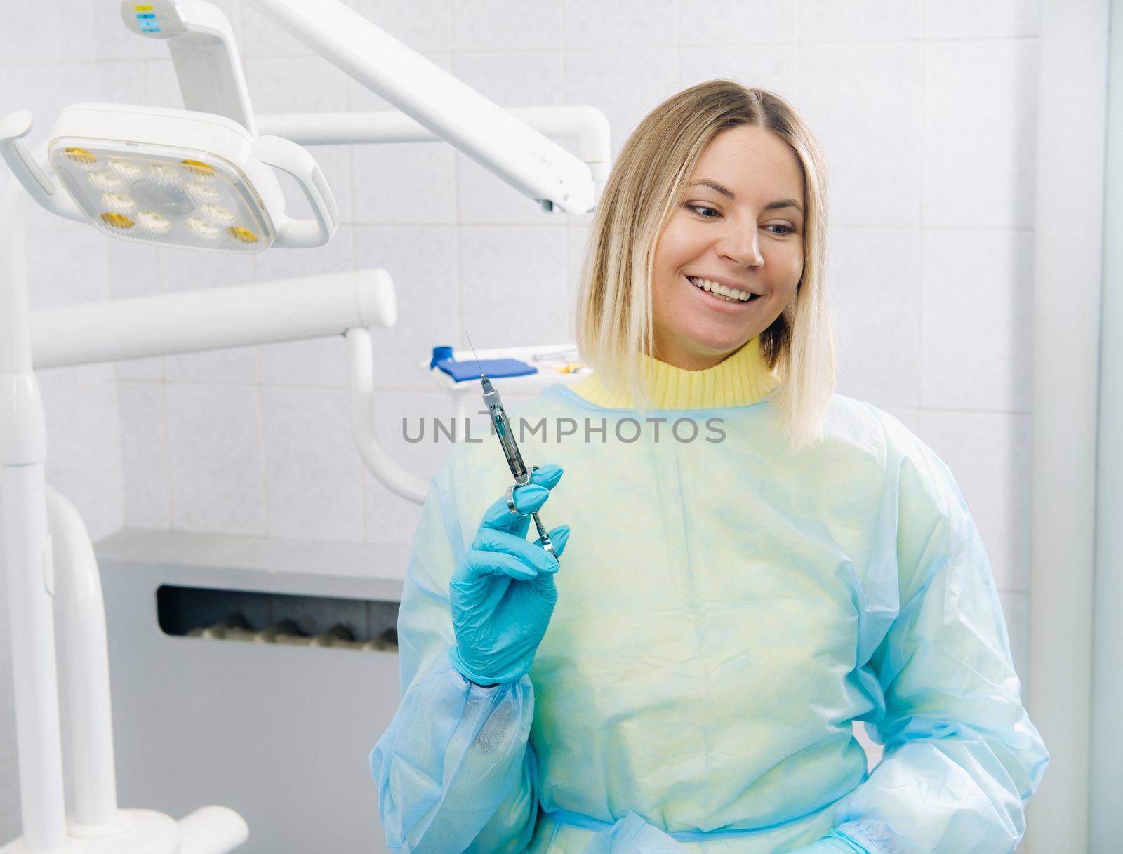 The dentist holds an injection syringe for the patient in the office by Lobachad