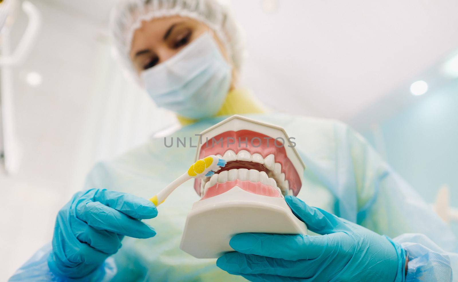 A model of a human jaw with teeth and a toothbrush in the dentist's hand by Lobachad