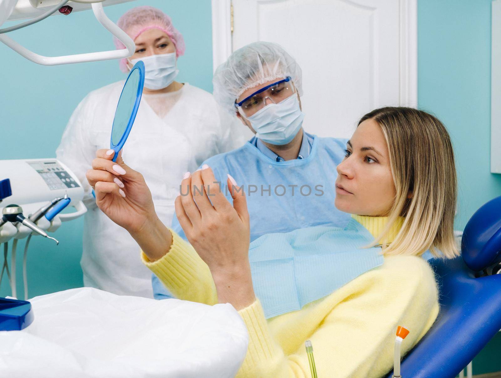 The dentist shows the client the results of his work in the mirror.The client smiles.