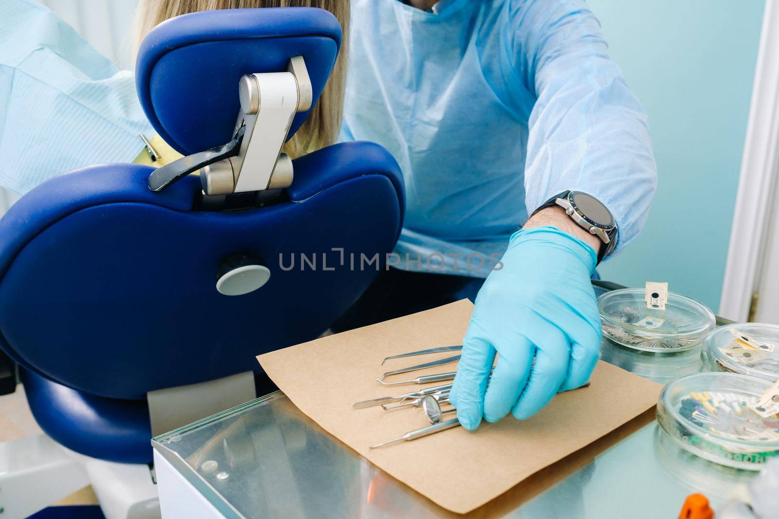 a dentist wearing gloves in the dental office holds a tool before working by Lobachad