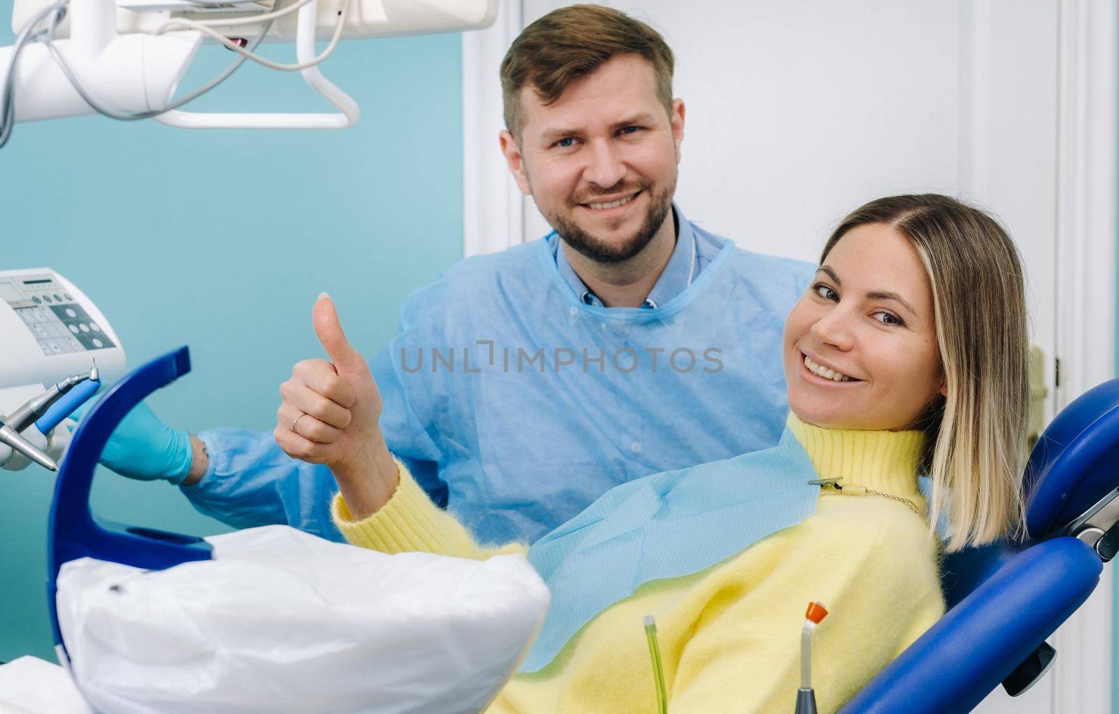 A beautiful girl patient is sitting in the dentist's office at the reception and next to the doctor.