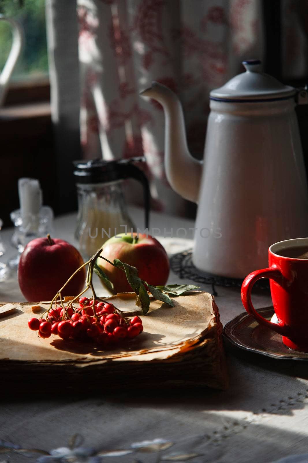 Still life in old rustic kitchen with red apples and a bunch of red rowan lying on old book, autumn morning tea concept. by Vera_FoodandGarden
