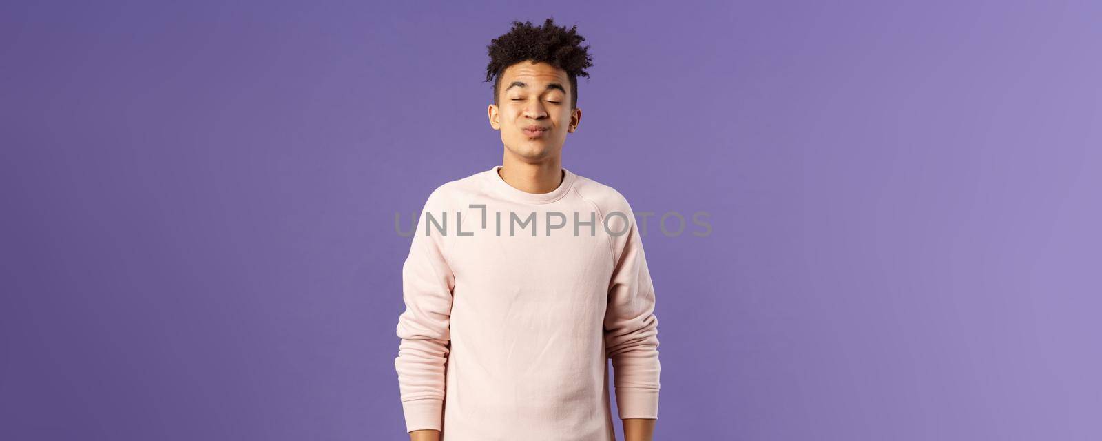Portrait of cute and silly, young hispanic trying to kiss girl after date for the first time, leaning with folded lips and closed eyes towards her, making funny smile, standing purple background.