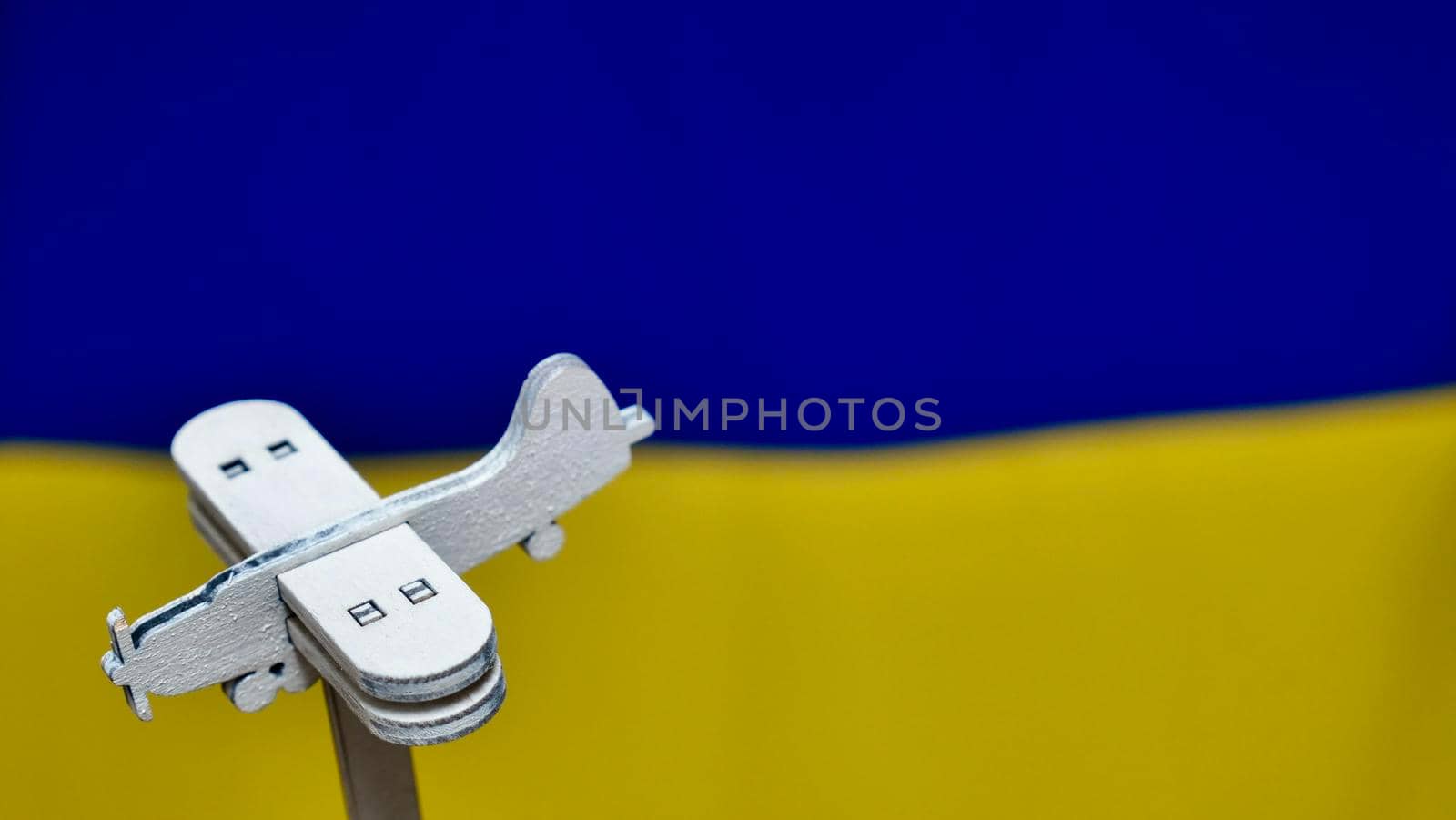 Wooden plane against background of Ukrainian flag by OksanaFedorchuk