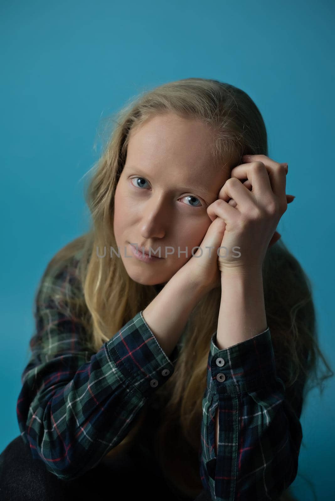A young Ukrainian woman on an isolated blue background in the studio. Modern blonde is sad during the war in Ukraine for the support of peace