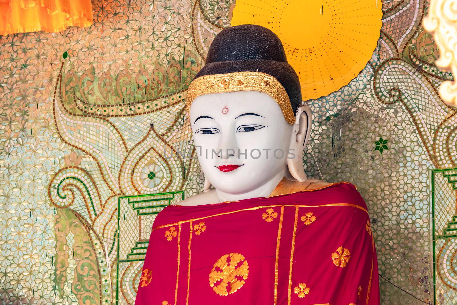A large Buddha figure in front of a mosaic in the Shwedagon Pagoda at Rangon in Myanmar