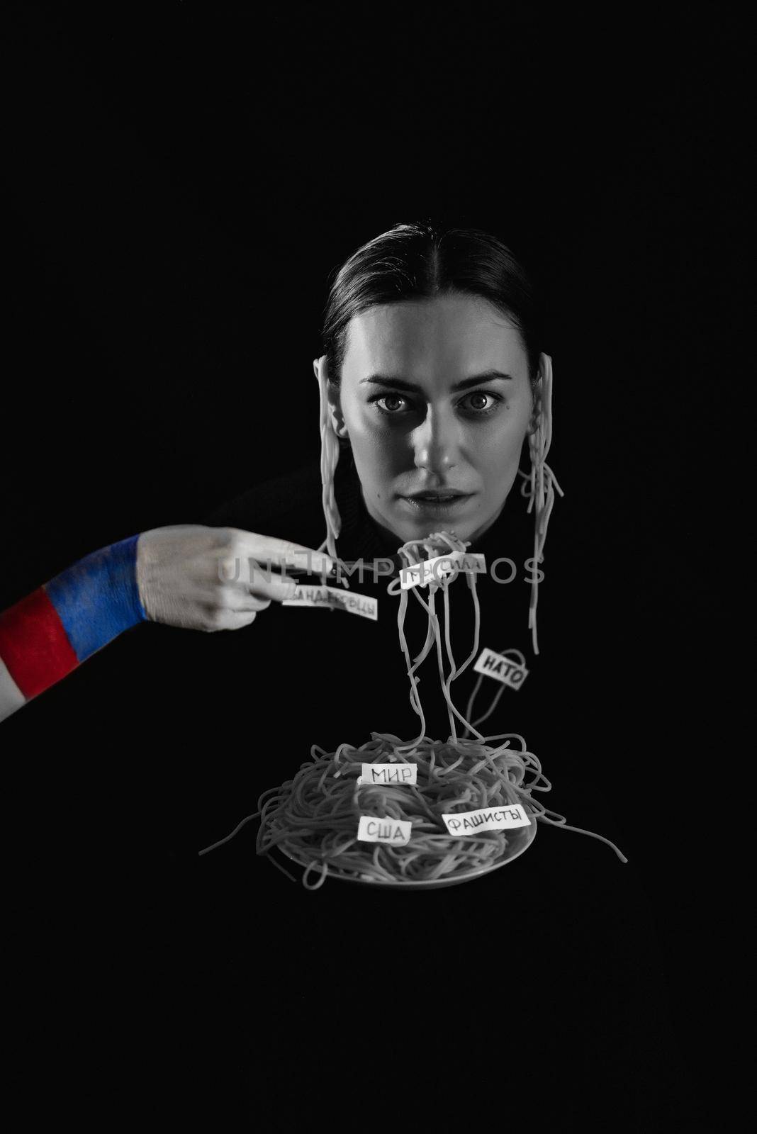 Russian propaganda. Hung spaghetti on the ears. Strangle a woman in war. Black white vertical photo of a young Caucasian woman