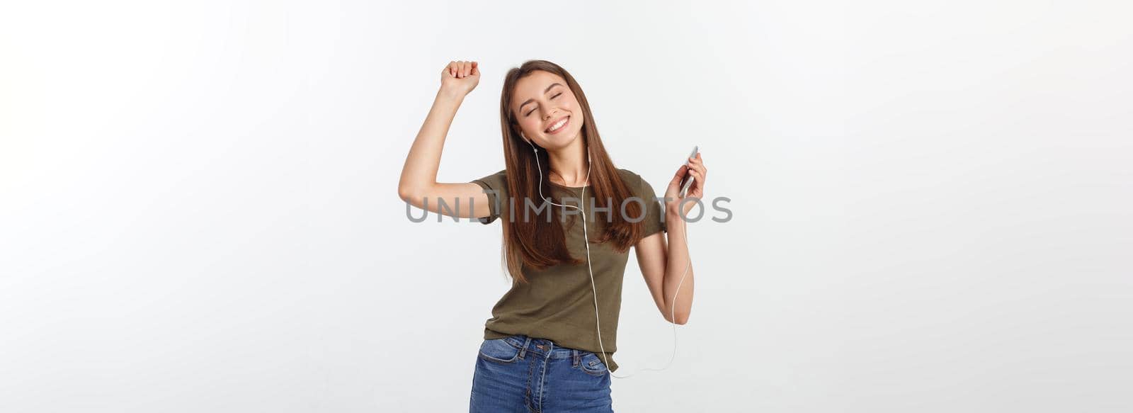 Portrait of a cheerful cute woman listening music in headphones and dancing isolated on a white background