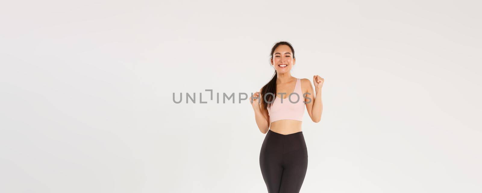 Sport, gym and healthy body concept. Full length of encouraged and motivated asian brunette girl ready for fitness training, fist pump and shouting in rejoice, gain goal with workout training app by Benzoix