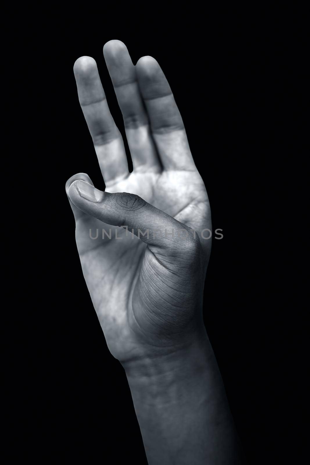 Shot of male hands demonstrating the Bhudy Yoga Mudra. Bhudy Yoga Mudra with pinky touched to thumb forming the mudra isolated on a black colored background. Vertical shot. by mirzamlk