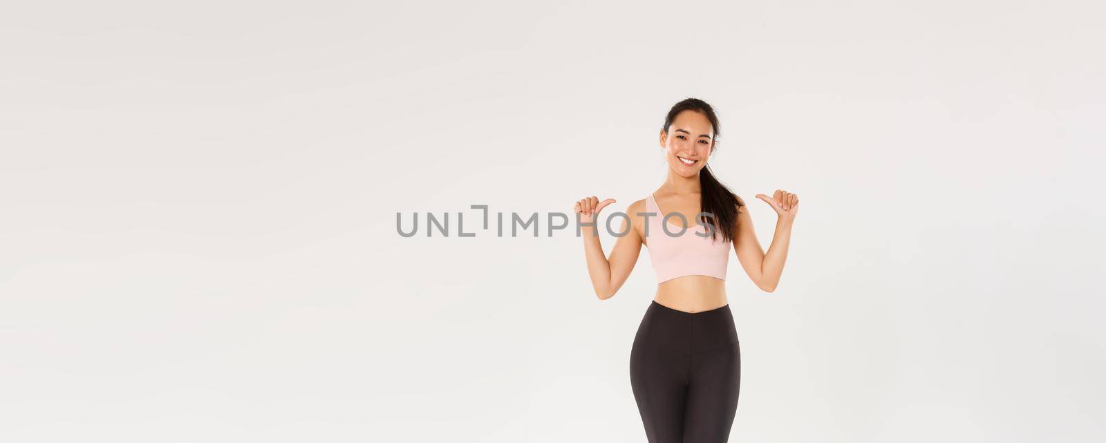 Full length of professional fitness coach, asian girl athelte pointing at herself and smiling happy, workout in gym, gaining perfect body with training, wearing sportswear, white background by Benzoix