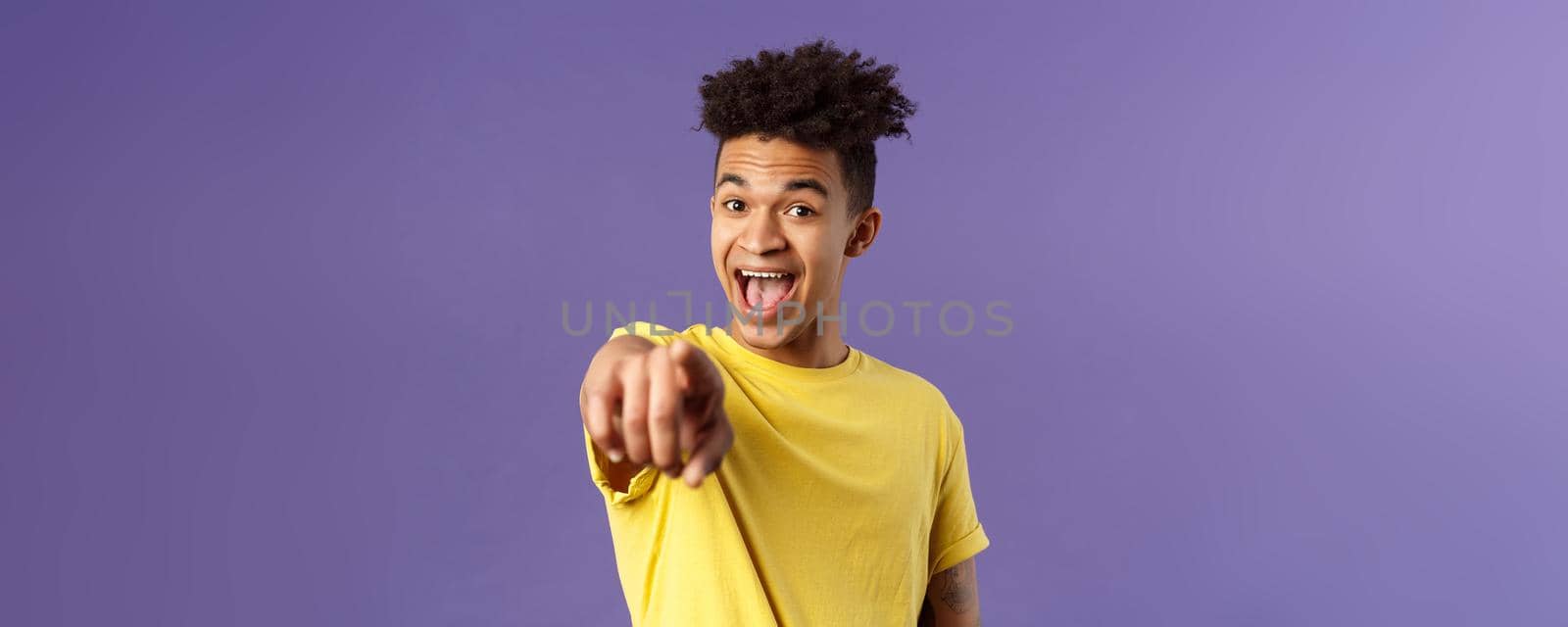 Close-up portrait of upbeat, amazed hispanic man with dreads, young student pointing finger at camera and laughing, recognize someone familiar, standing purple background by Benzoix