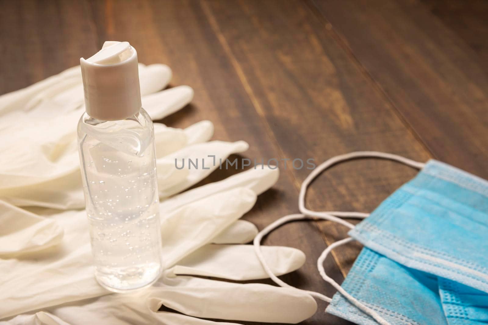 medical latex gloves, protective masks and hand sanitizer gel bottle for protection on wooden background. Useful for pandemic prevention concept