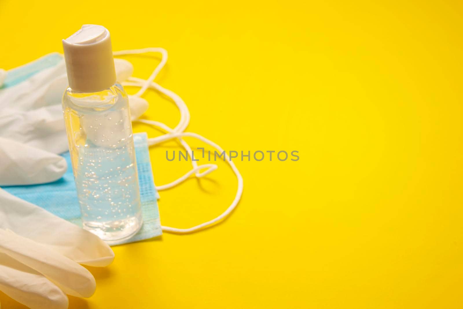 medical latex gloves, protective masks and hand sanitizer gel bottle for protection on yellow background. Useful for pandemic prevention concept