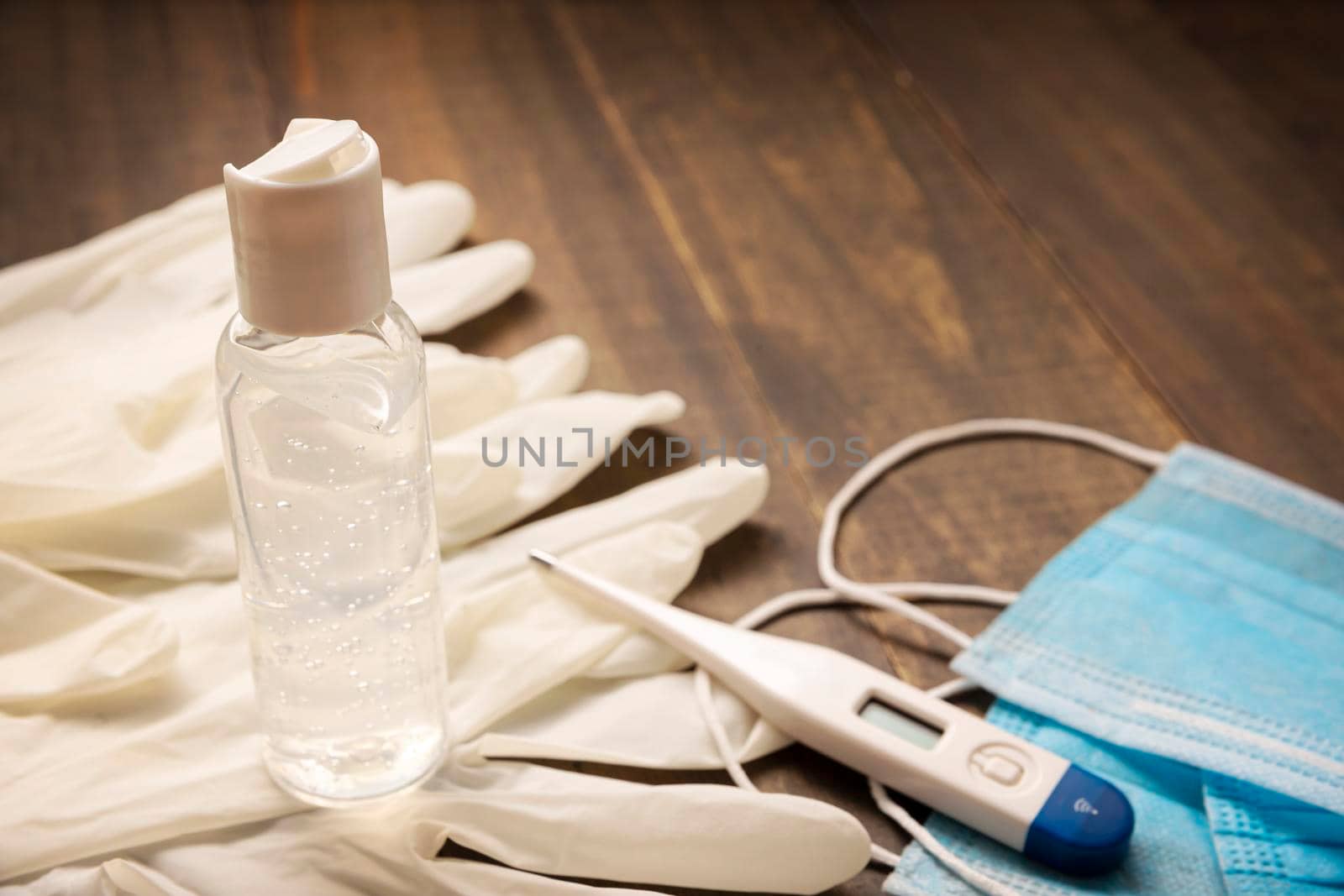 medical latex gloves, protective masks,thermometer and hand sanitizer gel bottle for protection on wooden background. Useful for pandemic prevention concept