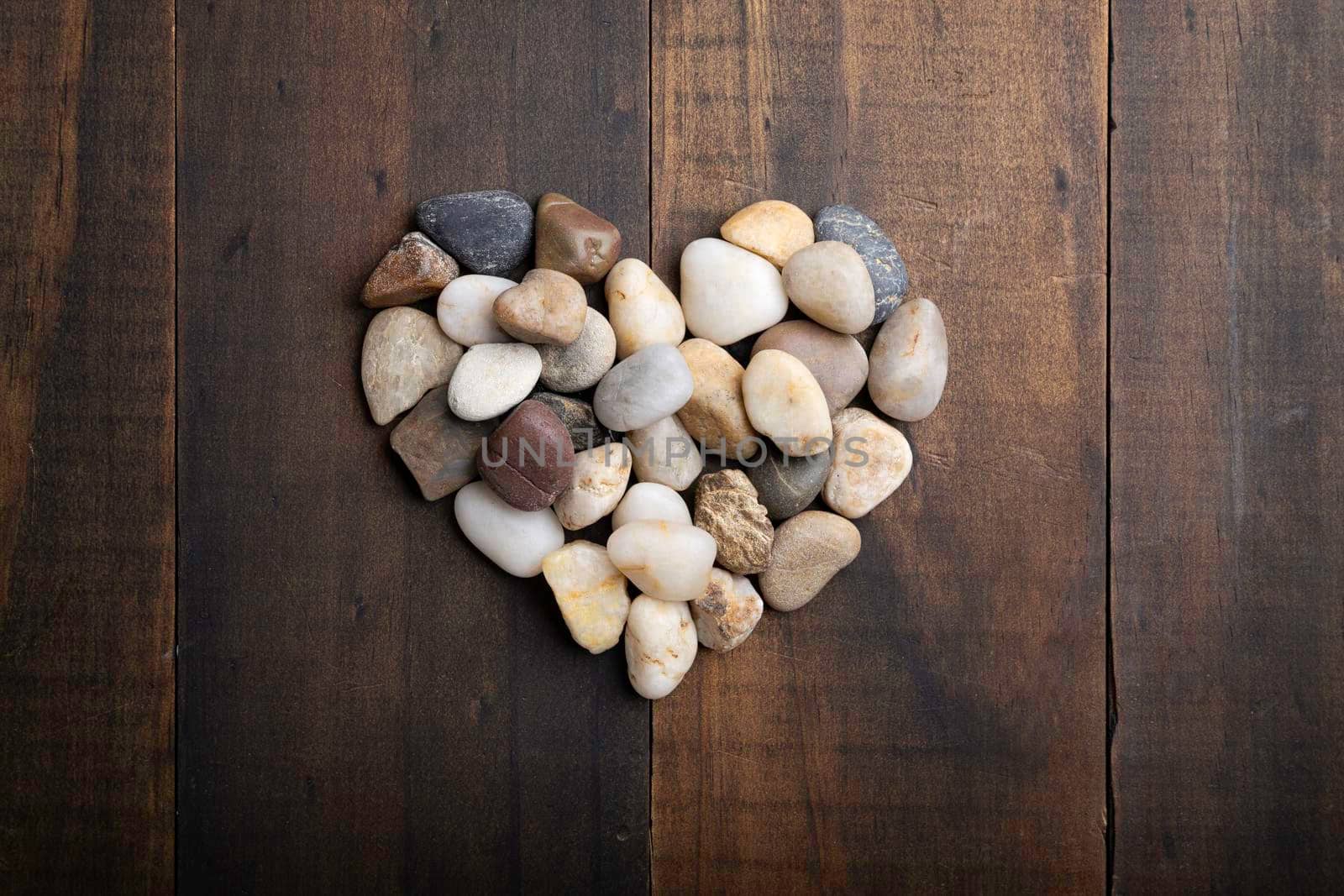 love concept image of heart shape made of round pebbles on wooden background