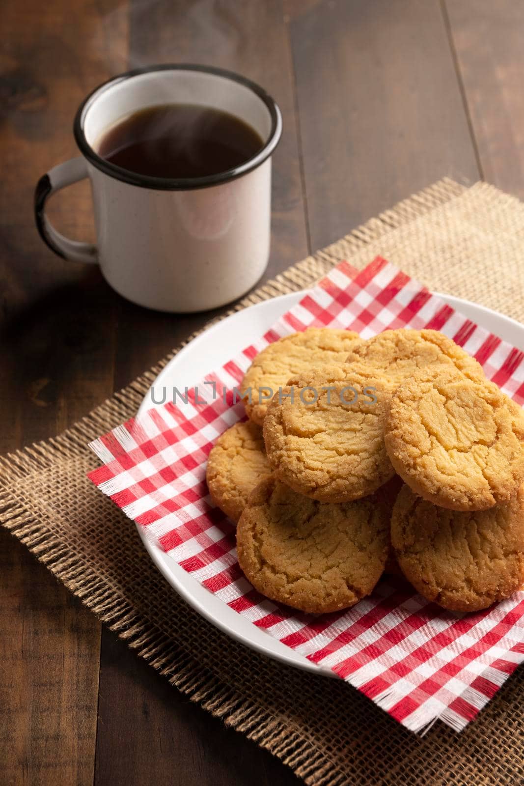 Homemade crunchy cookies and a black coffee cup on wooden rustic table