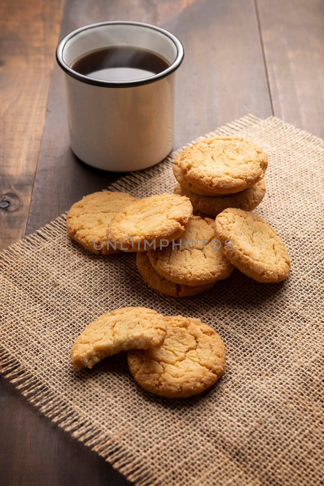 Homemade crunchy cookies and a black coffee cup on wooden rustic table