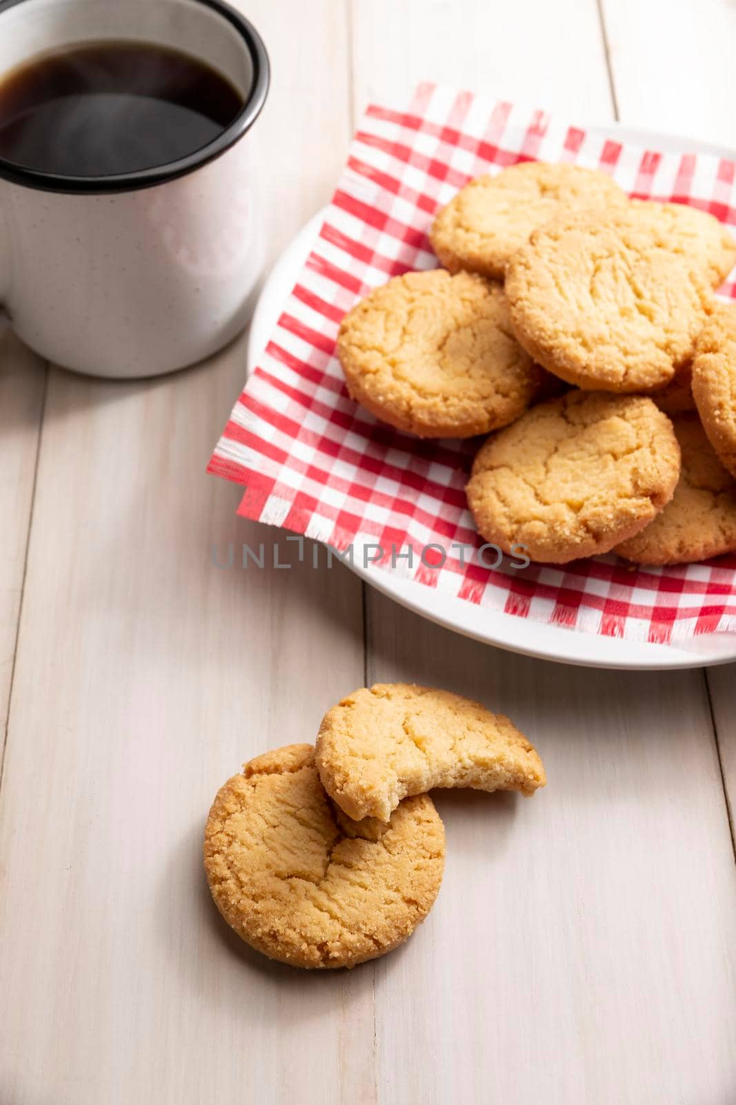 Homemade crunchy cookies and a coffee cup on white wooden rustic table