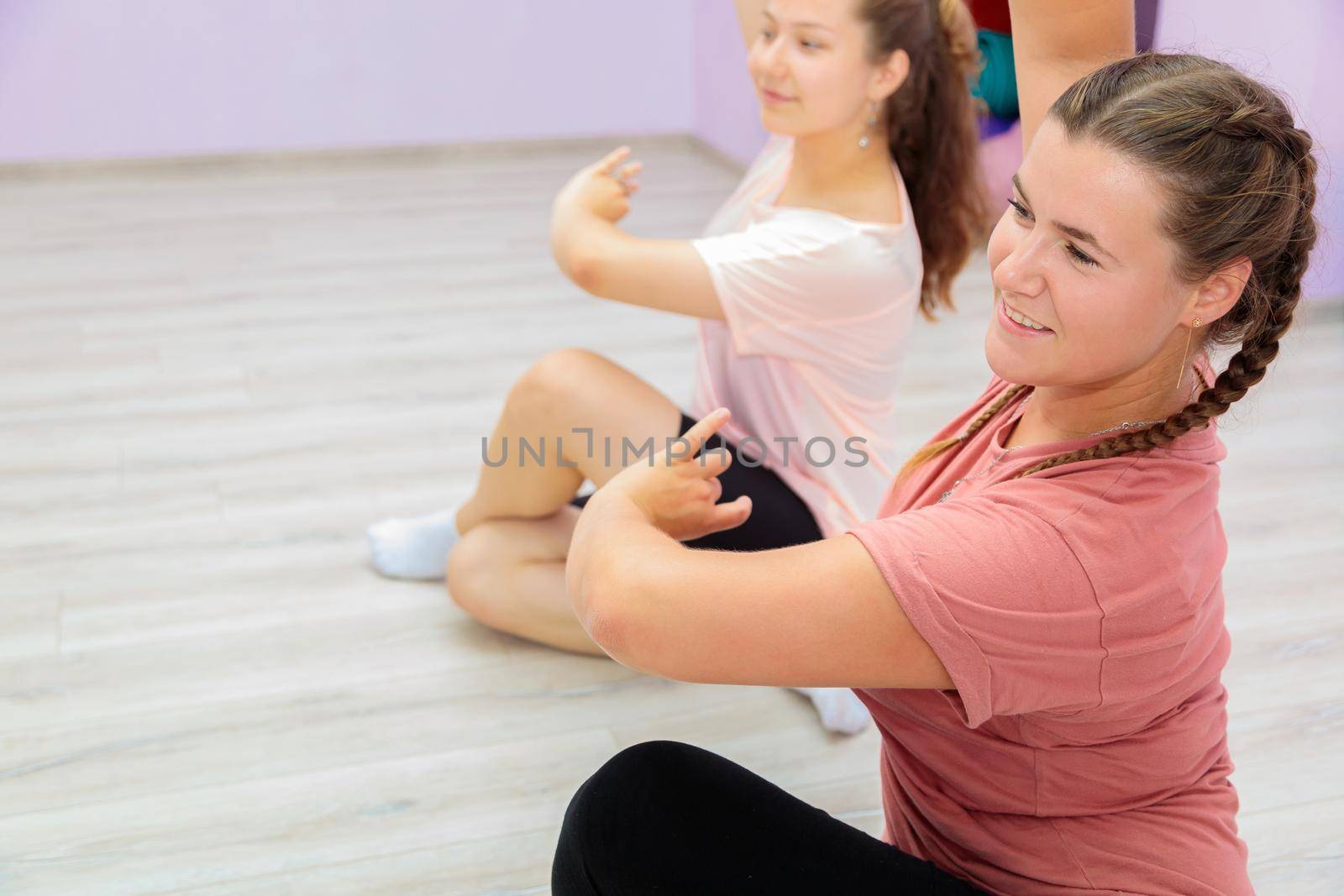 Girl dance instructor shows the elements of the number to another girl. Dance training.