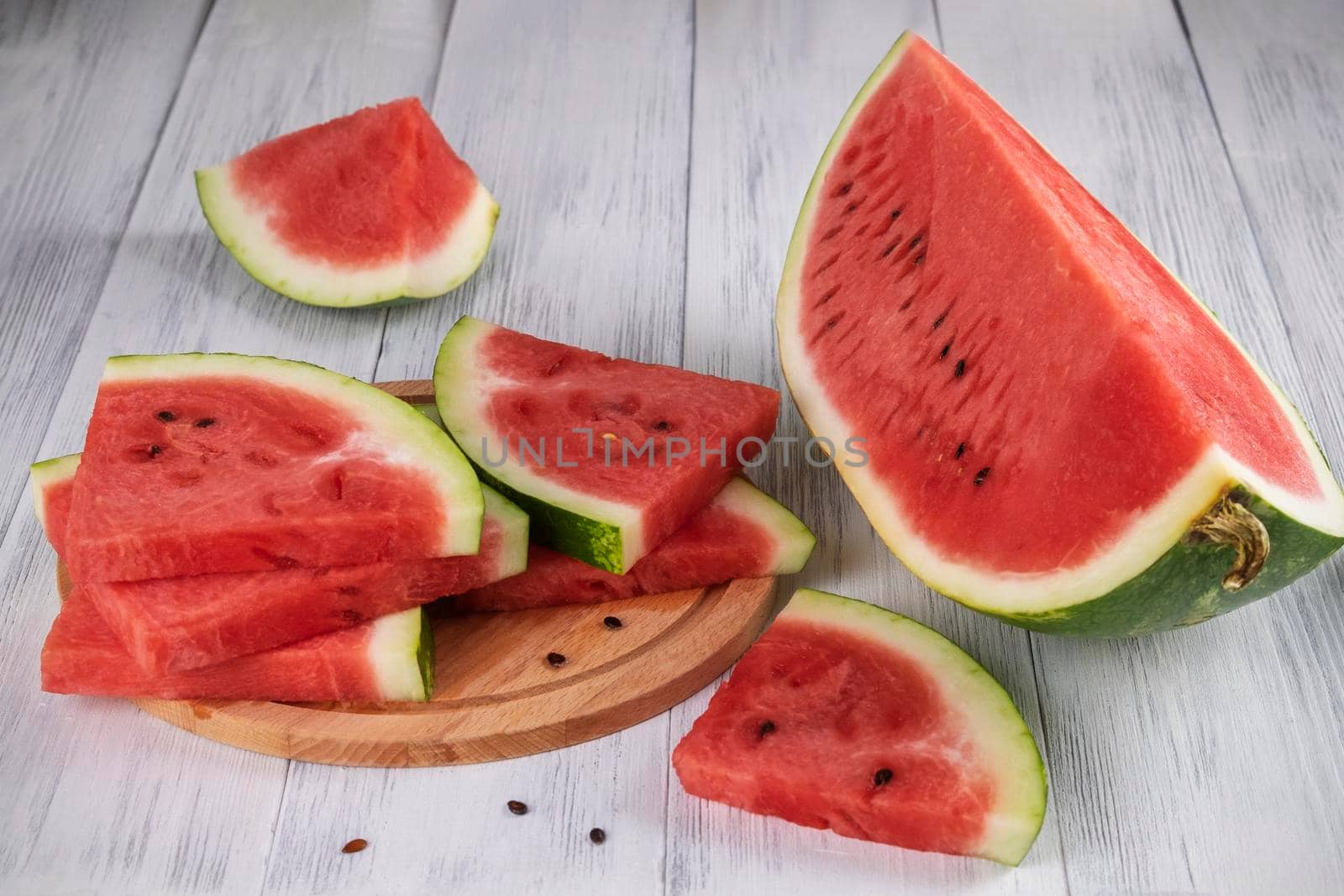 Close-up of sliced pieces of ripe red watermelon on a light wooden surface. Healthy food concept, summer food. Selective focus.