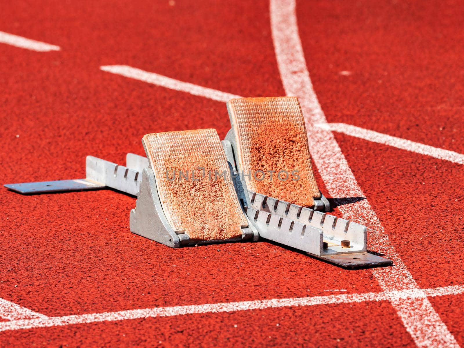 Side view of worn out starting blocks on running tracks. Red running tracks lanes at track and field stadium. Sport accessory.