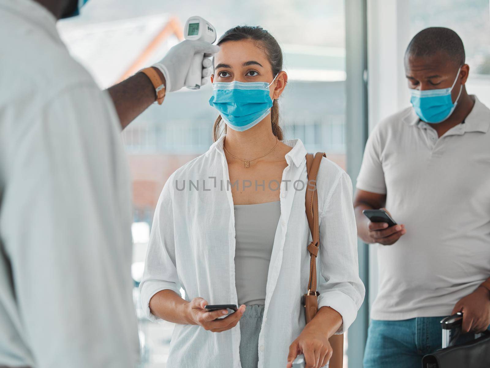 Compliance, travel and covid restrictions by security scanning tourist temperature with a infrared thermometer at airport. Worker checking or fever for other corona related symptoms at work.