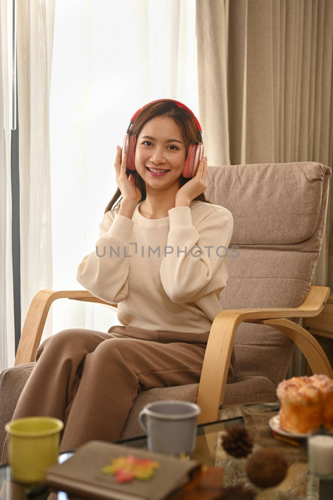 Pleasant woman in warm sweater listening to music on wireless headphone, enjoy stress free peaceful mood in an autumn day.