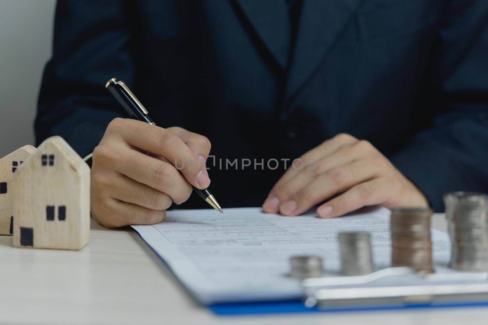 Sign the house approval document. Real estate appraisal, buy and sell houses, business concept finance.businessman holding pen and signing documents at desk