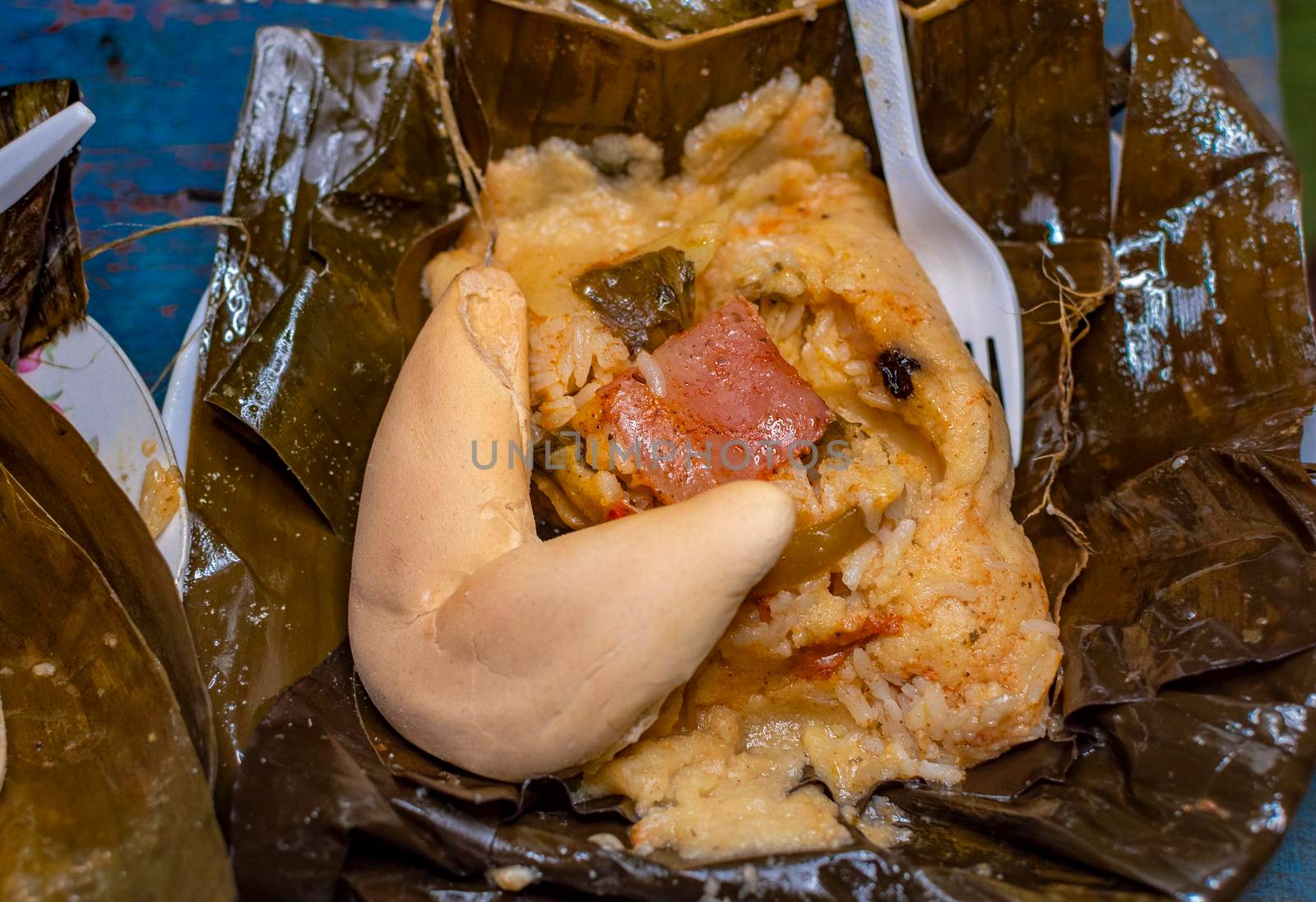 Nacatamal served with bread in a banana leaf on the table. Traditional Nacatamal served in banana leaf, Nicaraguan Nacatamal with bread on the table, Traditional Venezuelan Hallaca served by isaiphoto