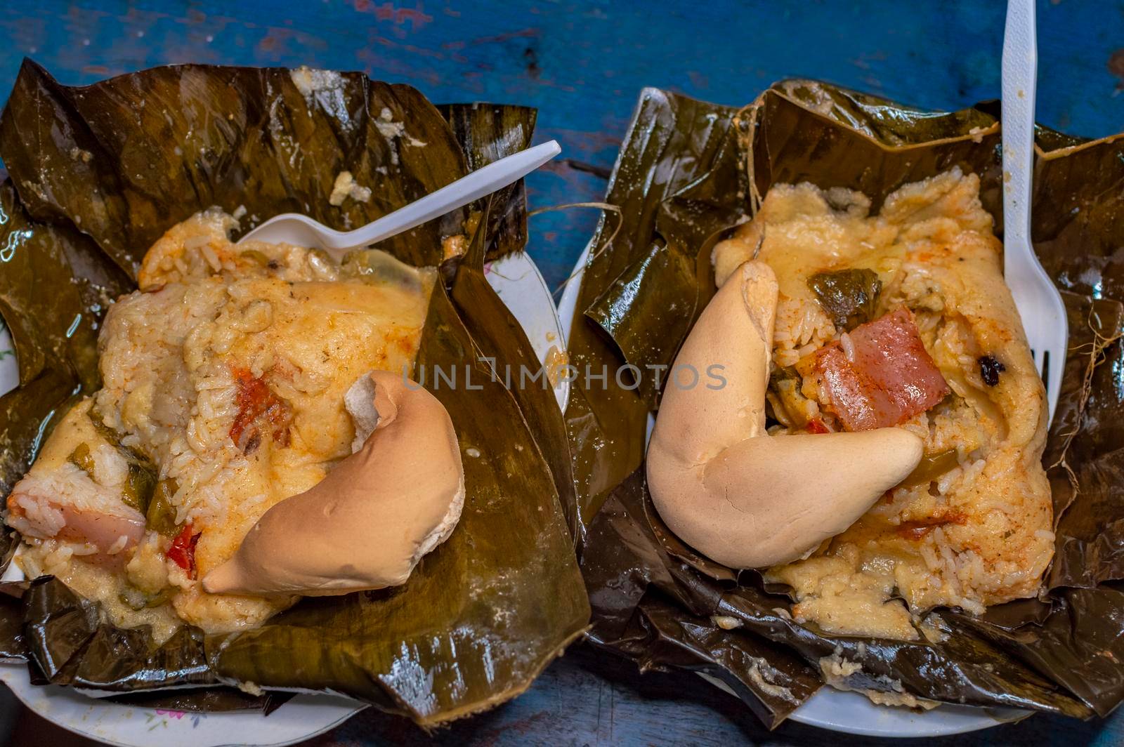Two Nacatamales served in a banana leaf on the table. Top view of two traditional Nacatamales served on banana leaf, Two Nacatamales with bread served on the table, Venezuelan Hallaca served