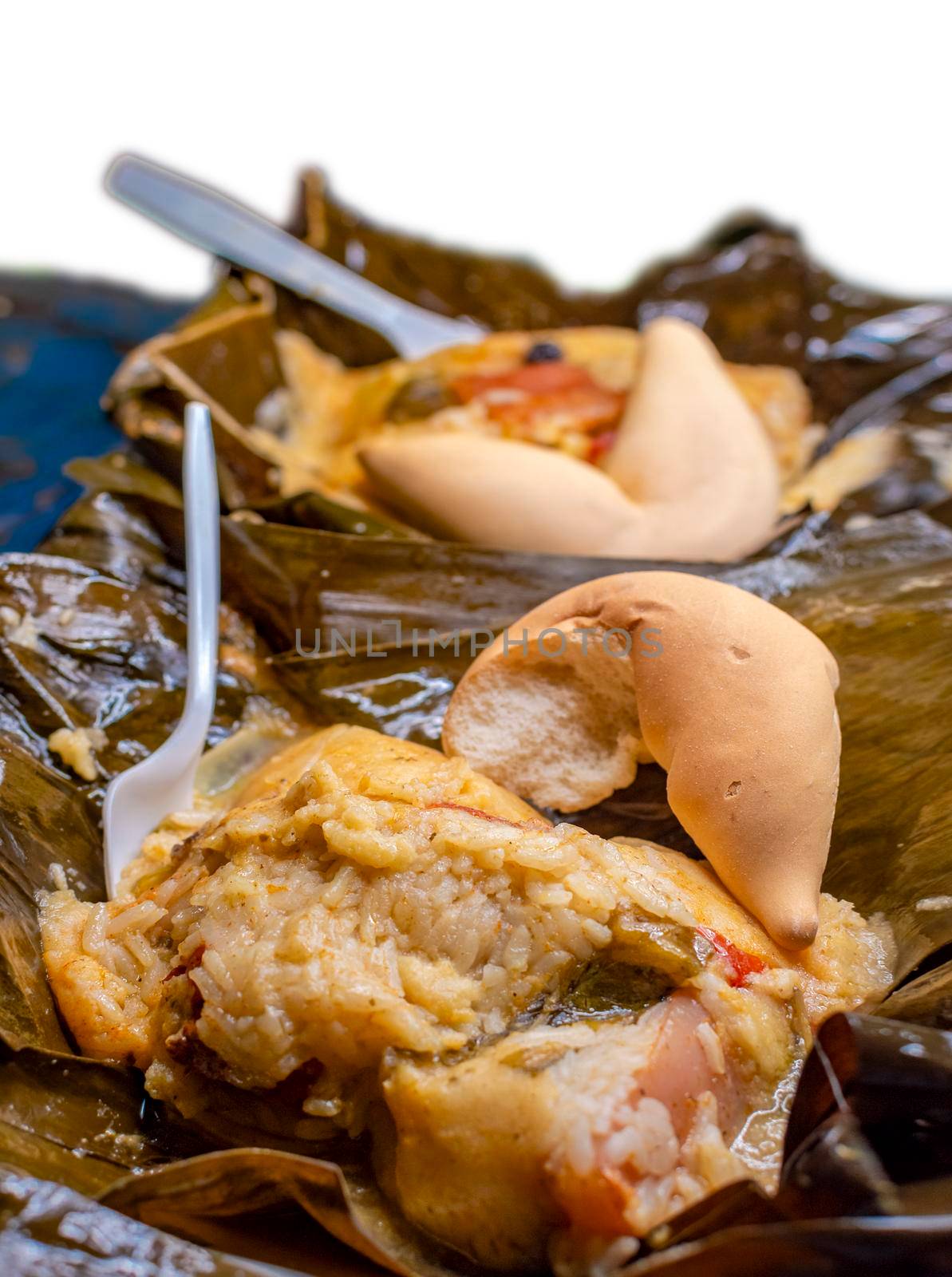 Close up of two Nacatamales in banana leaf served on table. Two Nacatamales served in a banana leaf on a wooden table. Nacatamales with bread served at the table, Traditional Hallaca served