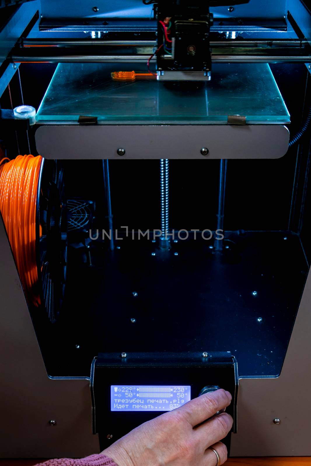 printing on a 3d printer. orange trident is printed with plastic on a 3d printer