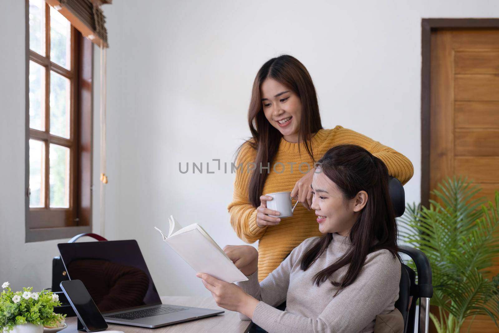 two friends talking and smiling one to each other in small break of studying with cup of coffee in hands.