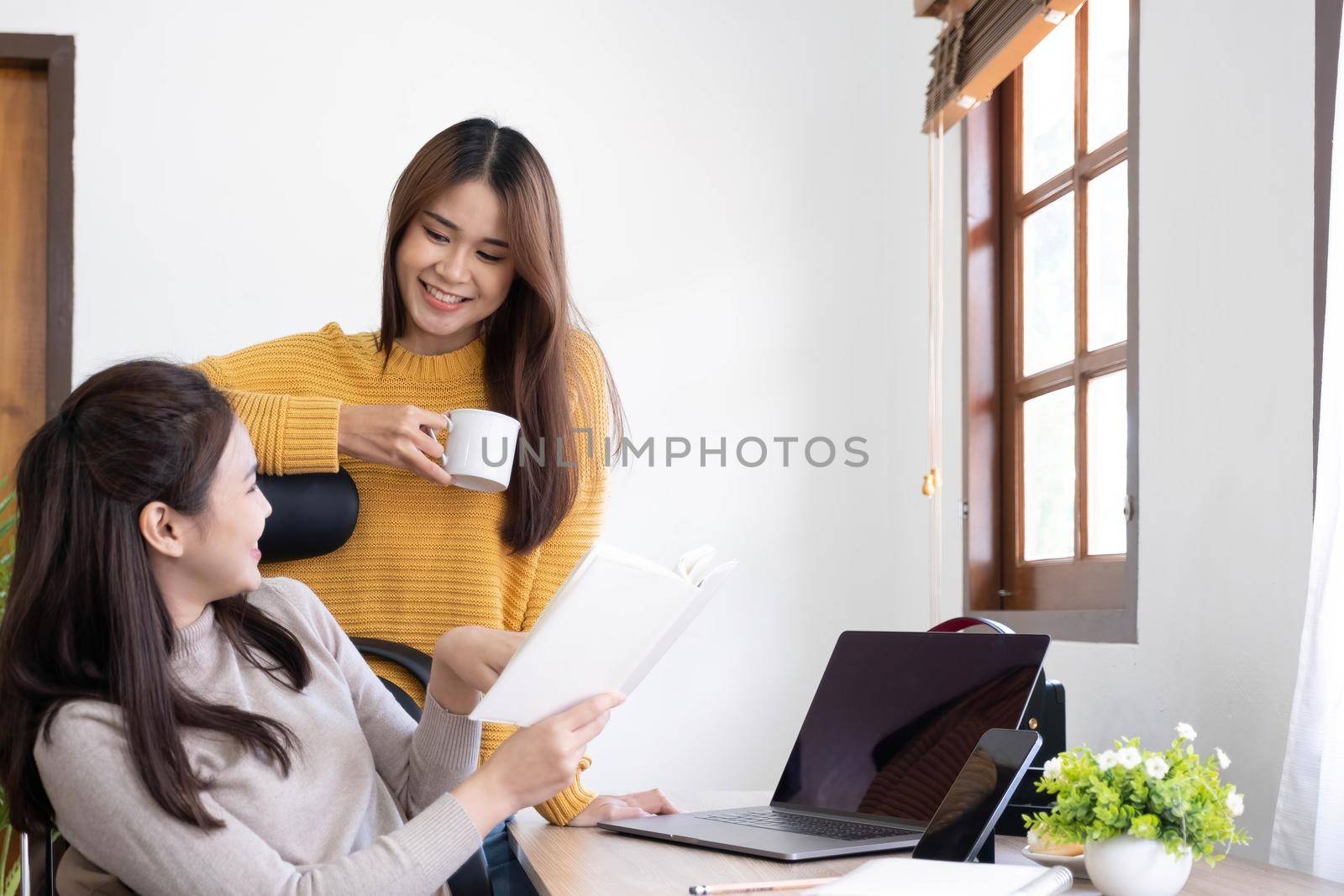two friends talking and smiling one to each other in small break of studying with cup of coffee in hands.
