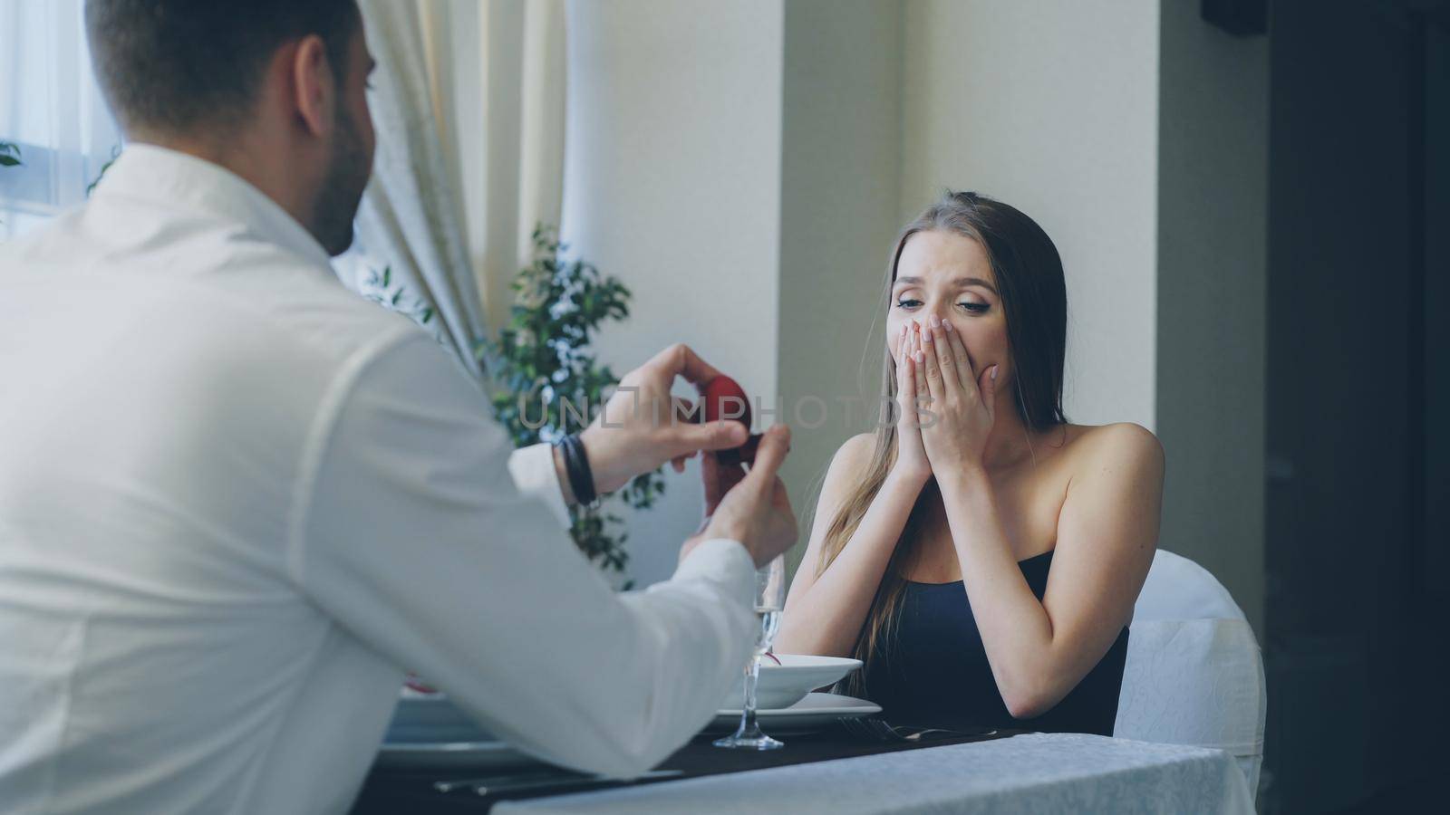 Pretty girl in beautiful dress is saying yes to marriage proposal. Love, restaurant and romance concept.