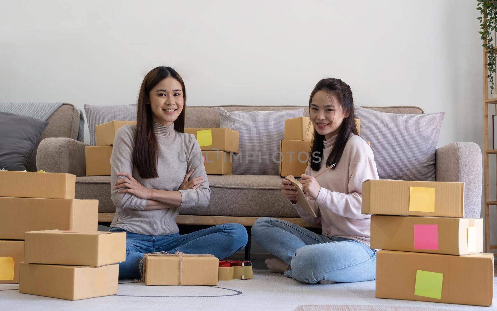 Portrait of Starting small businesses SME owners, two Asian woman check online orders Selling products working with boxs freelance work at home office, sme business online small medium enterprise by wichayada