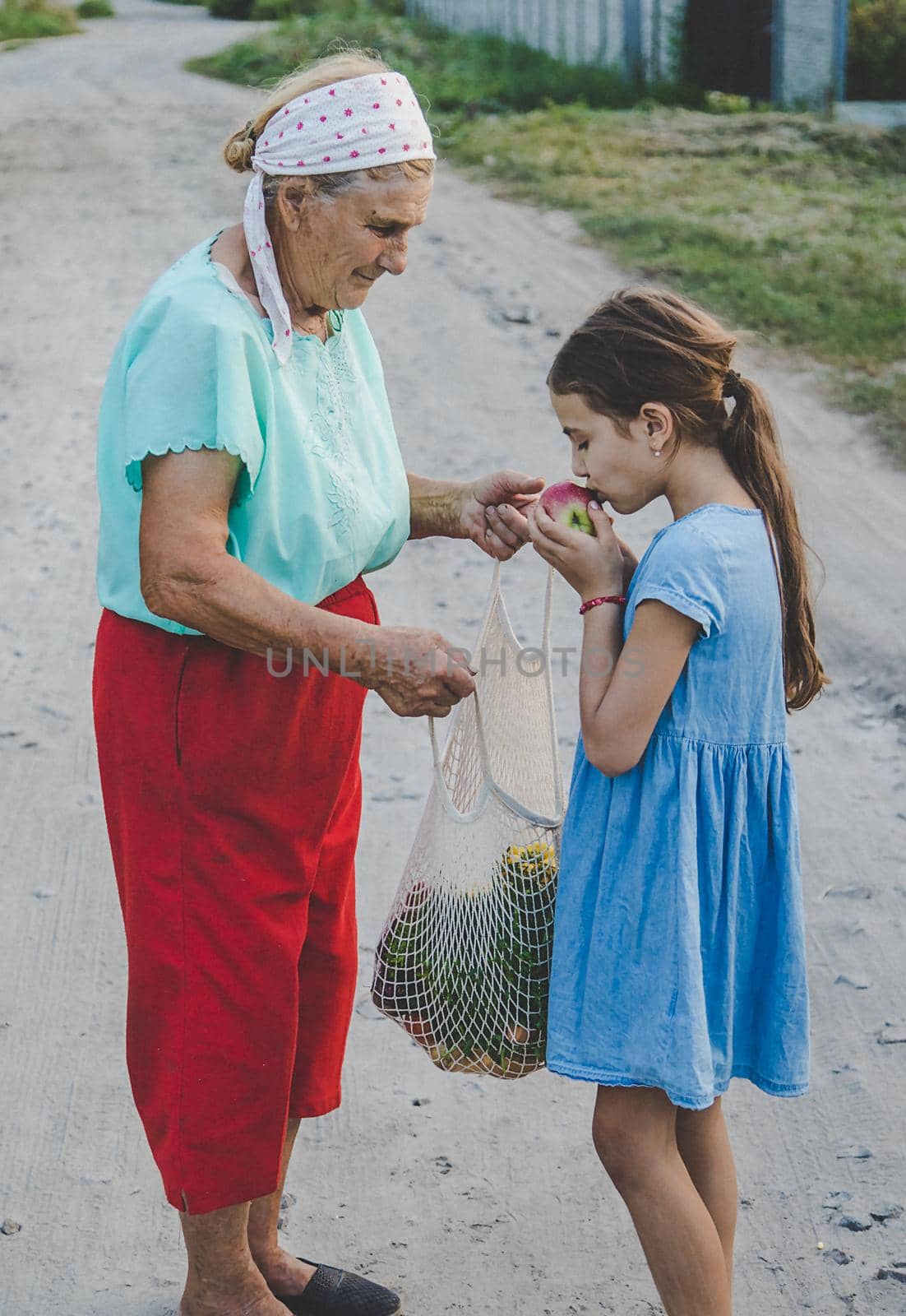 Child and grandmother carry vegetables in a bag. Selective focus. by yanadjana
