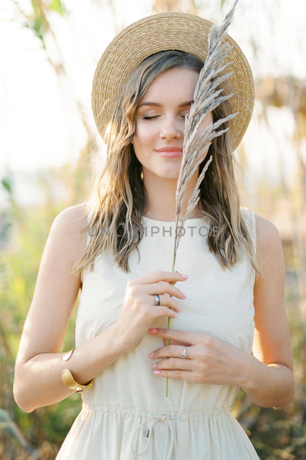 Dry branch of reed in the hands of a girl in a straw hat. Portrait. High quality photo