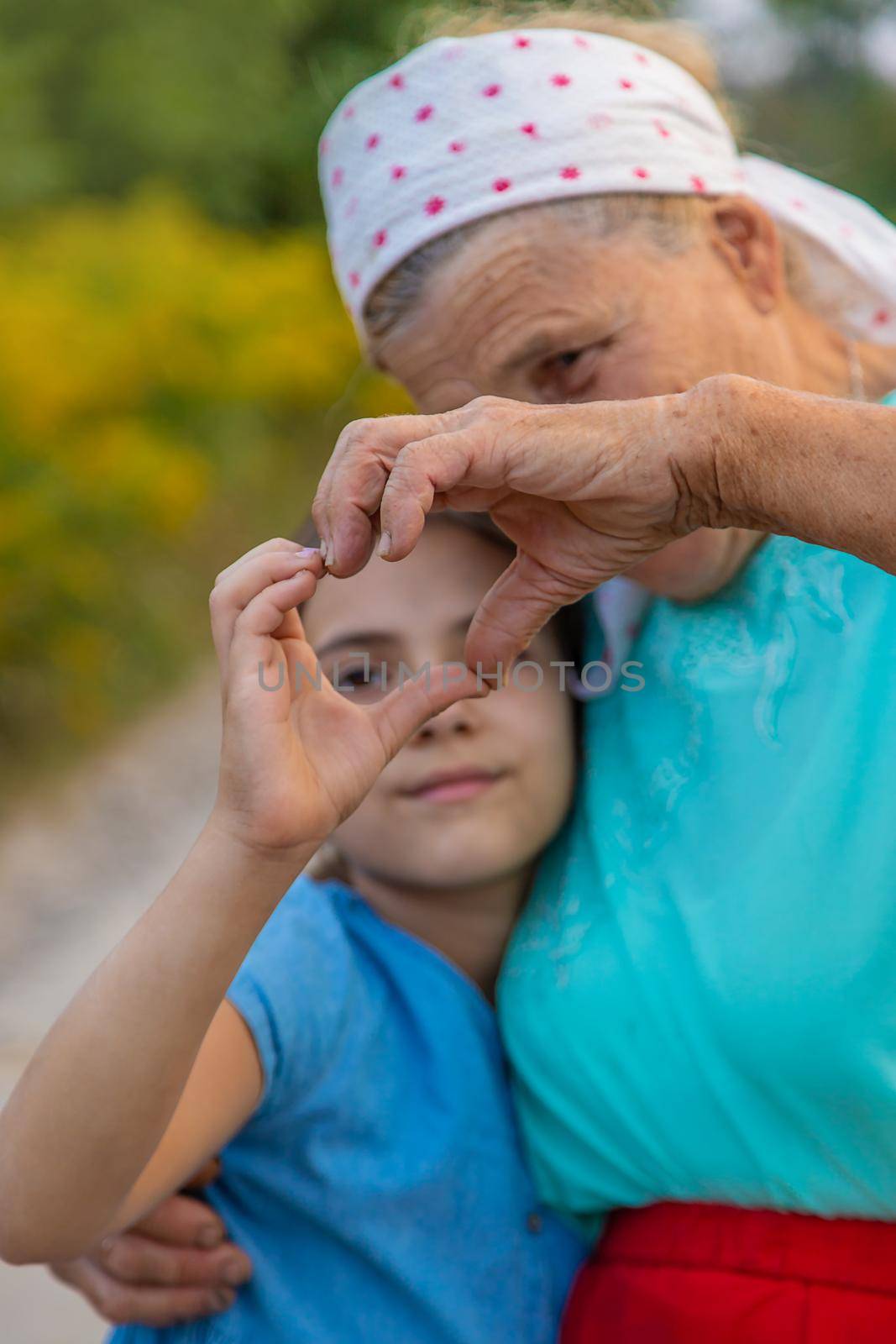 Grandmother and granddaughter make a heart with their hands. Selective focus. People.